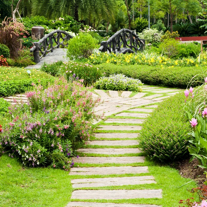 Jardin paysager avec allée en dalles de pierre naturelle traversant pelouse soignée