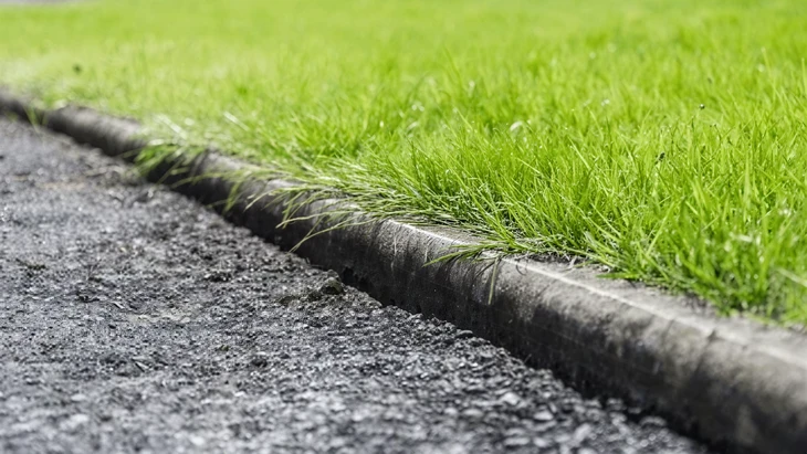 Aménagement paysager extérieur avec bordure décorative en blocs de béton texturé marron délimitant un massif végétal