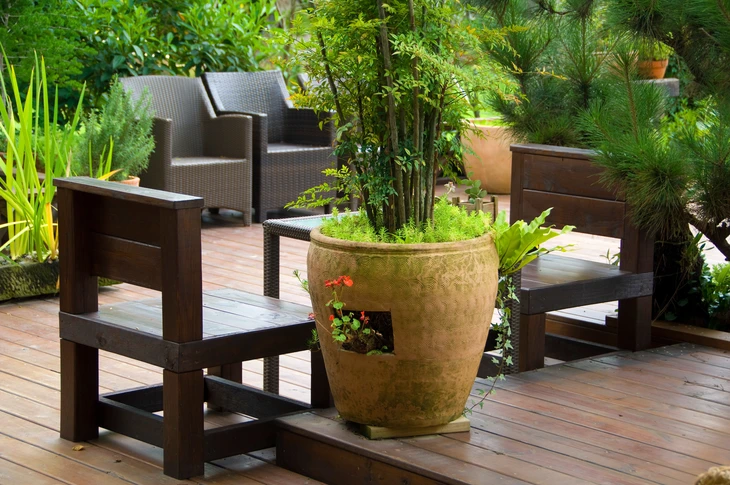 Espace détente extérieur dans jardin résidentiel avec mobilier en rotin tressé sur terrasse bois