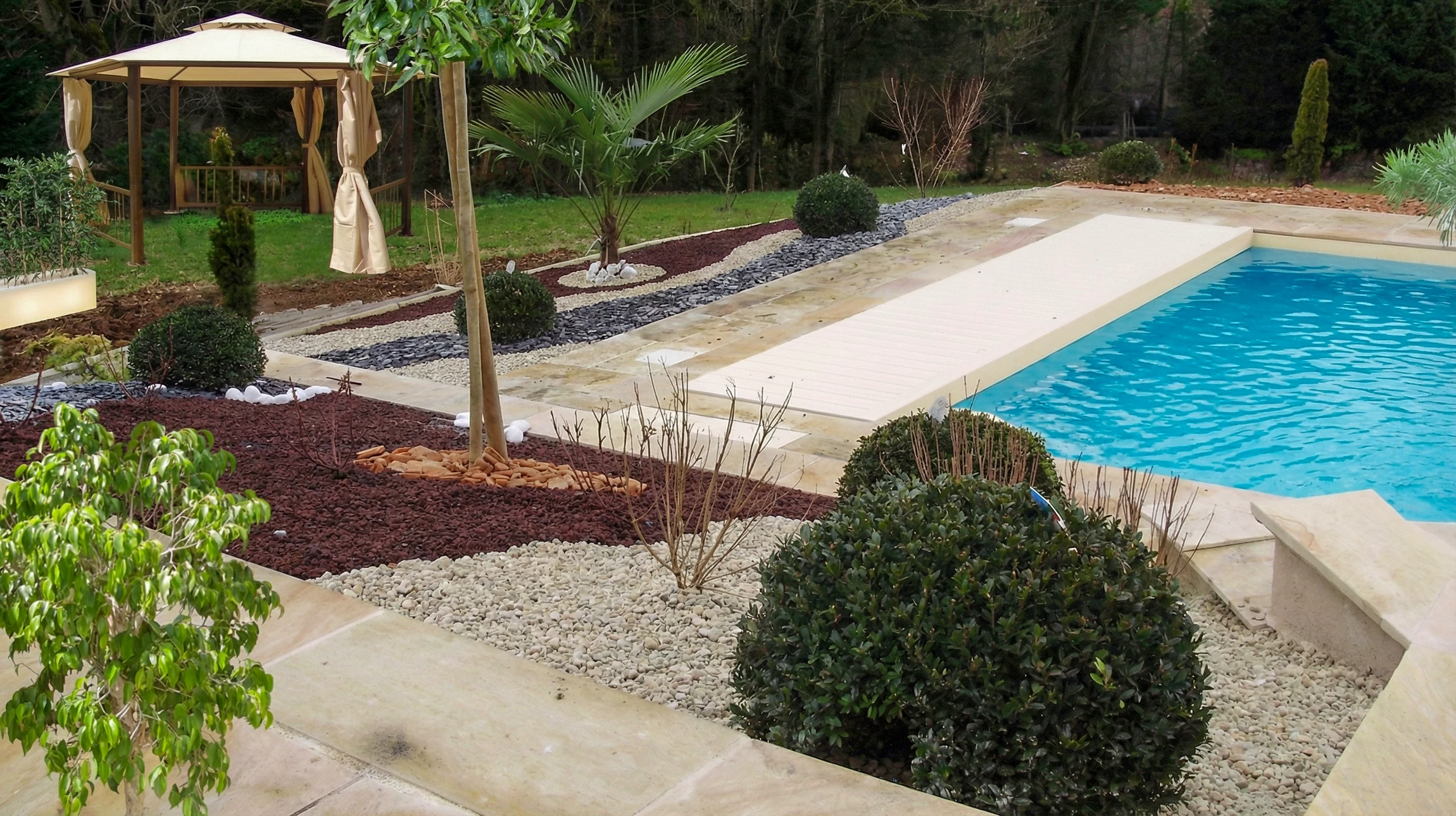 Terrasse en bois avec salon de jardin face &agrave; un bassin aquatique am&eacute;nag&eacute;